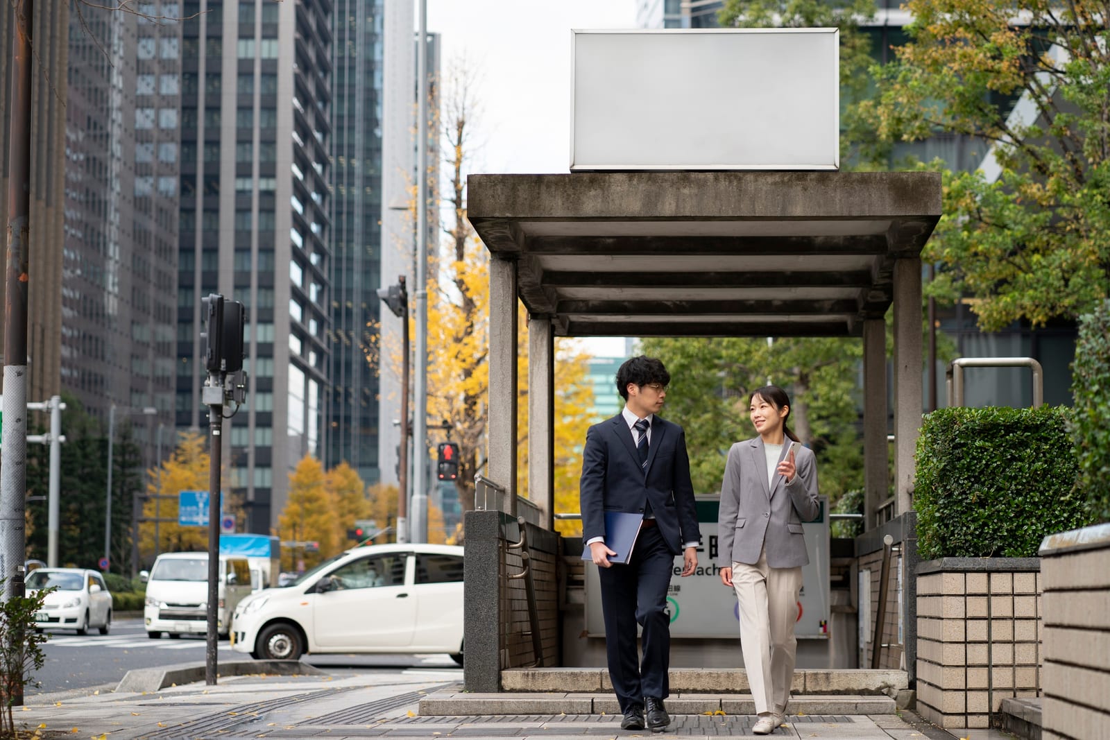 ビジネスパートナーの男女が、秋のオフィス街を歩きながら話している
